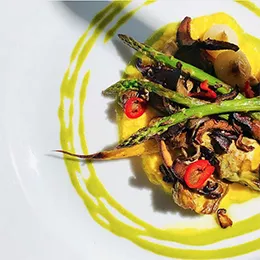 A Health-Supportive Culinary Arts class combined seared mushrooms, sauteed asparagus, roasted carrots, braised baby artichokes, grated fresh corn "polenta" and vegan cilantro pesto in this stunning dish.