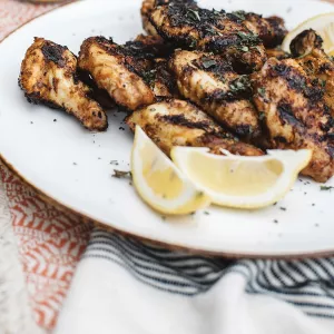 Grilled chicken plated with lemon wedges
