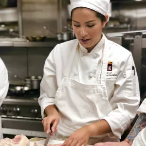 Maki Yazawa prepares chicken in an ICE LA Culinary Arts class.