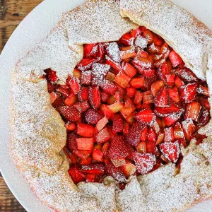 A rhubarb galette with bright red filling sits on a white plate