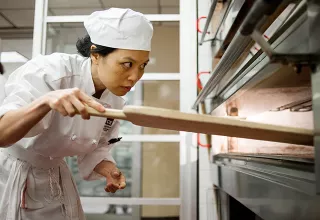 A student checks on breads in the oven