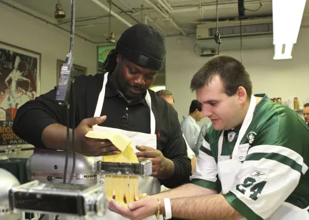 A New York Jets football player makes fresh pasta with a fan at ICE