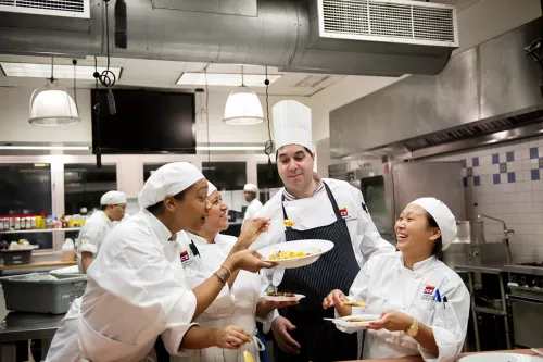 Students and chef instructors taste dishes
