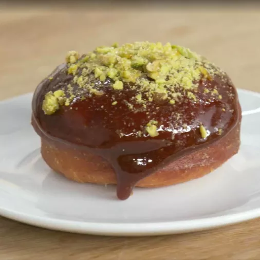 A Sicilian pistachio and calamansi donut sits on a white plate