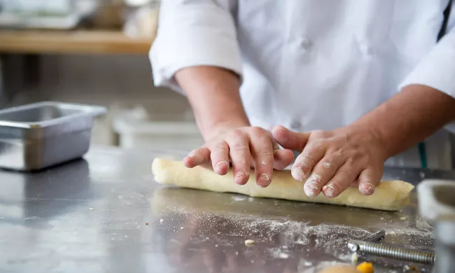 A culinary school student kneads pasta dough in the kitchen at ICE