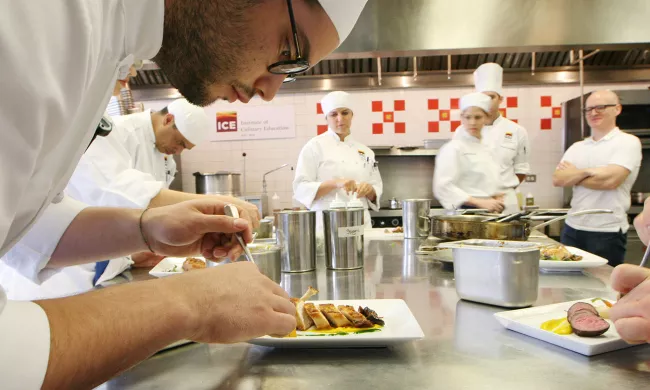 A student finishes plating a dish in class at ICE