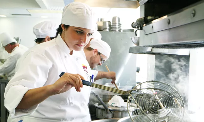 An ICE culinary arts student works over the stove