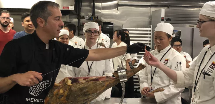 Manuel slices samples of jamon iberico for students to try.
