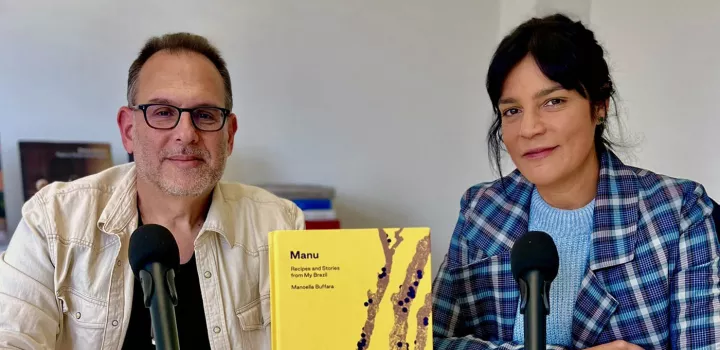 Andrew Friedman and Manu Buffara sit behind a copy of Manu's book