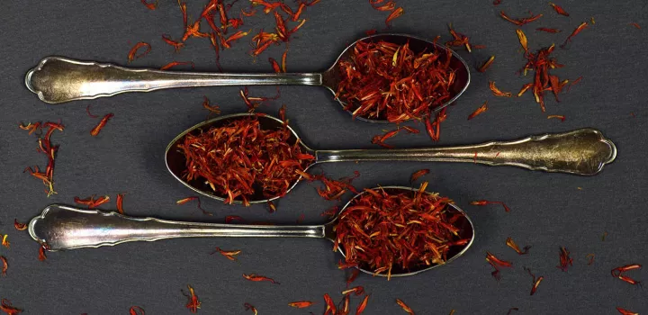 Red saffron leaves sit on three metal spoons