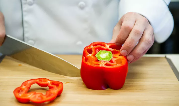 Slicing a red bell pepper on a cutting board
