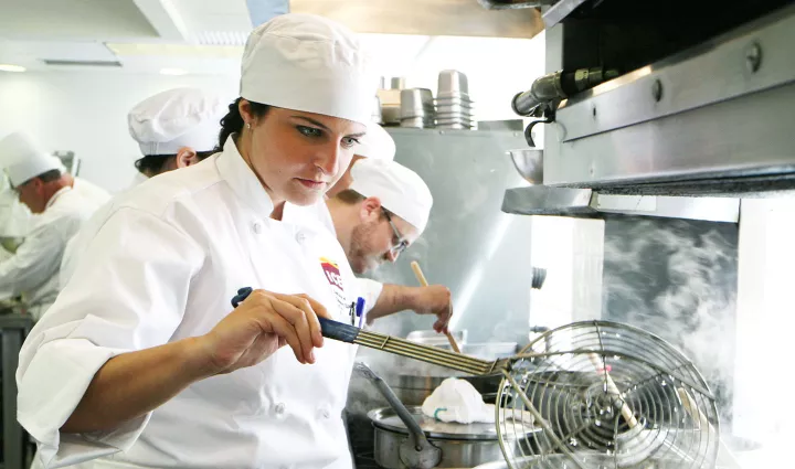 Culinary arts student cooks over the stove at the Institute of Culinary Education