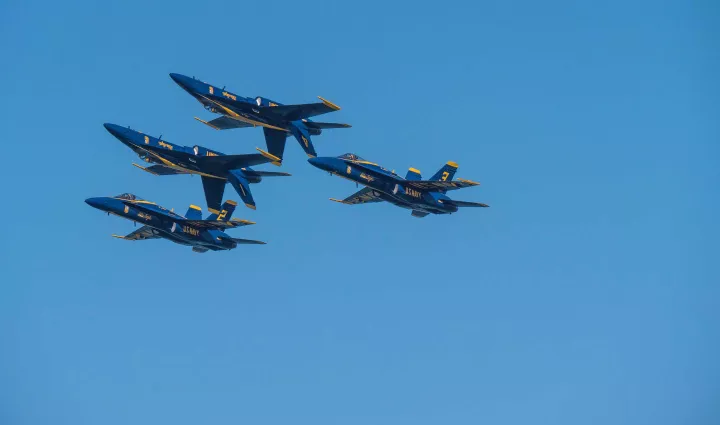 Navy military jets fly against a blue sky, photo by Raw Film via Unsplash
