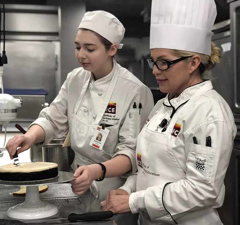 ICE Chef Missy Smith-Chapman and a student smooth a cake in class